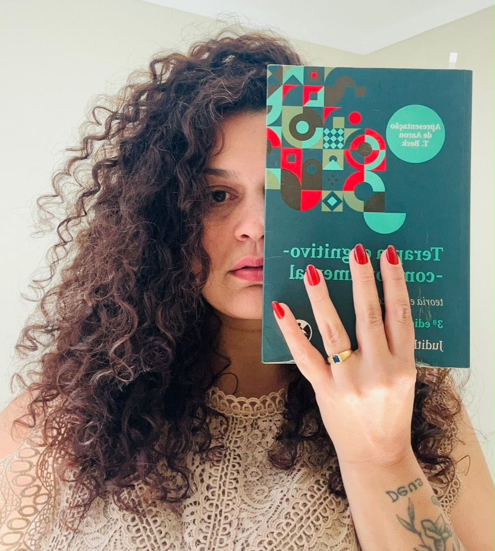Stephânia segurando o livro Terapia Cognitivo-Comportamental, de Judith Beck
